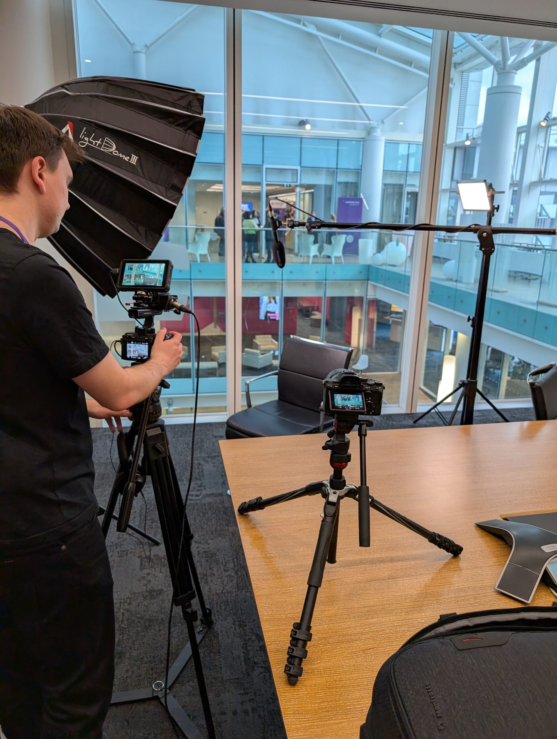 Video production setup with professional equipment including cameras, lights, and a backdrop in a modern office environment.