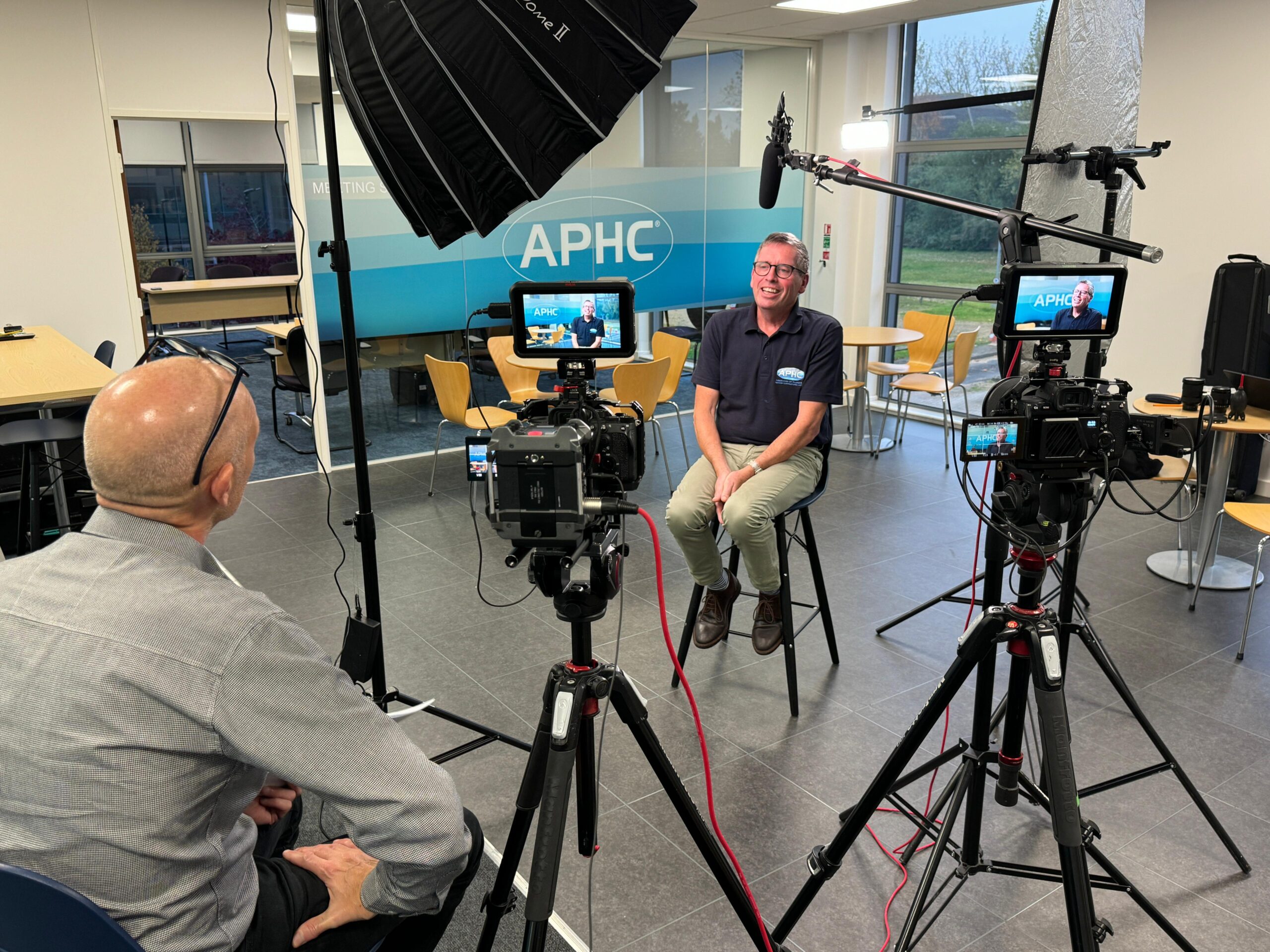 Behind-the-scenes of a video production shoot at APHC, featuring professional camera equipment, lighting, and an interview setup.