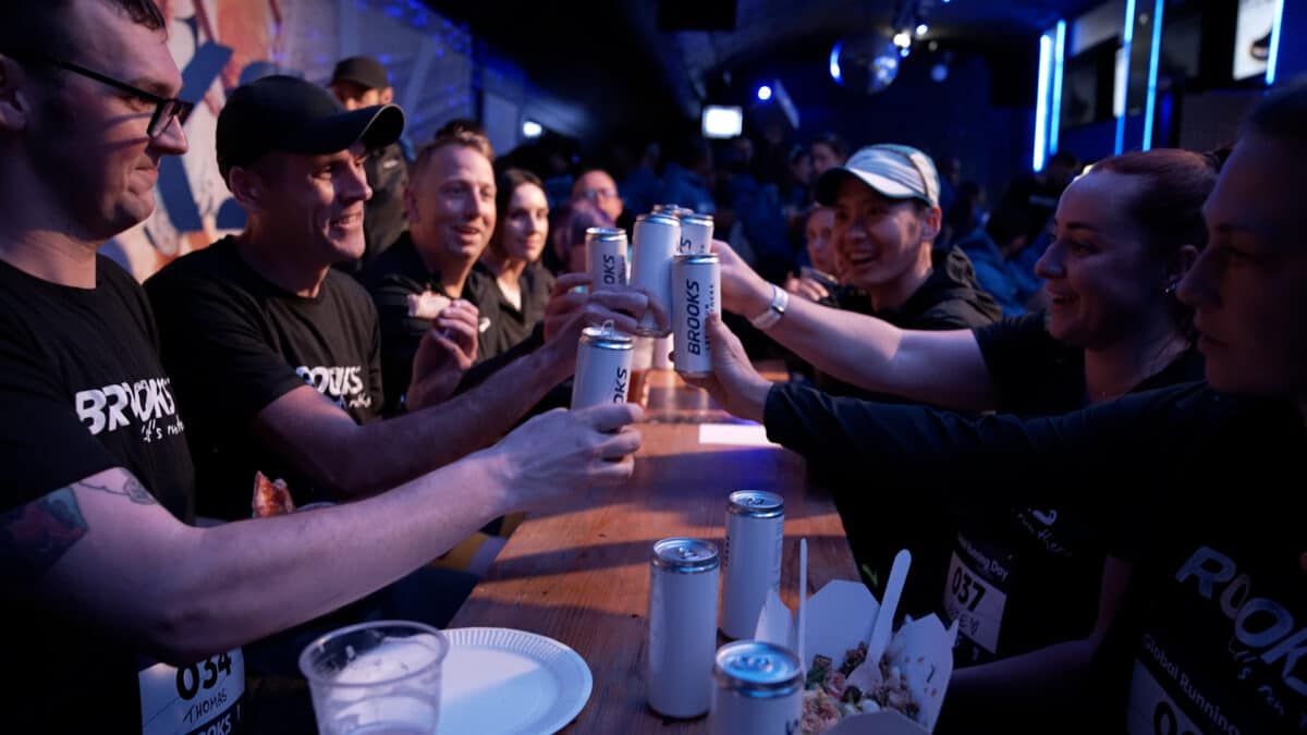 A group of friends joyfully toasting with cans at a lively social event, captured in a vibrant bar setting.