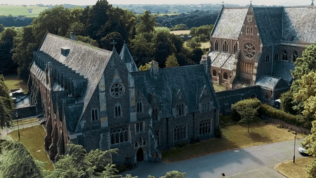 Aerial view of a historic gothic-style church surrounded by lush greenery, captured by drone photography.