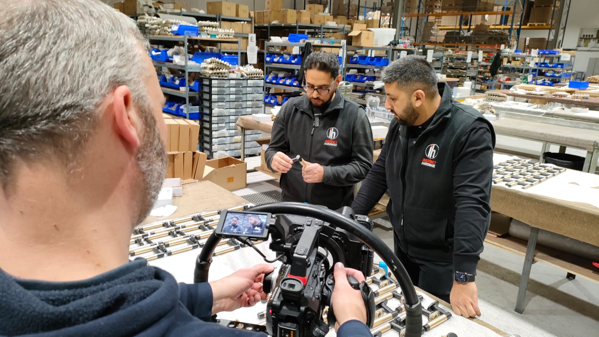 Behind the scenes of a video shoot in a manufacturing facility, featuring two employees discussing a product.